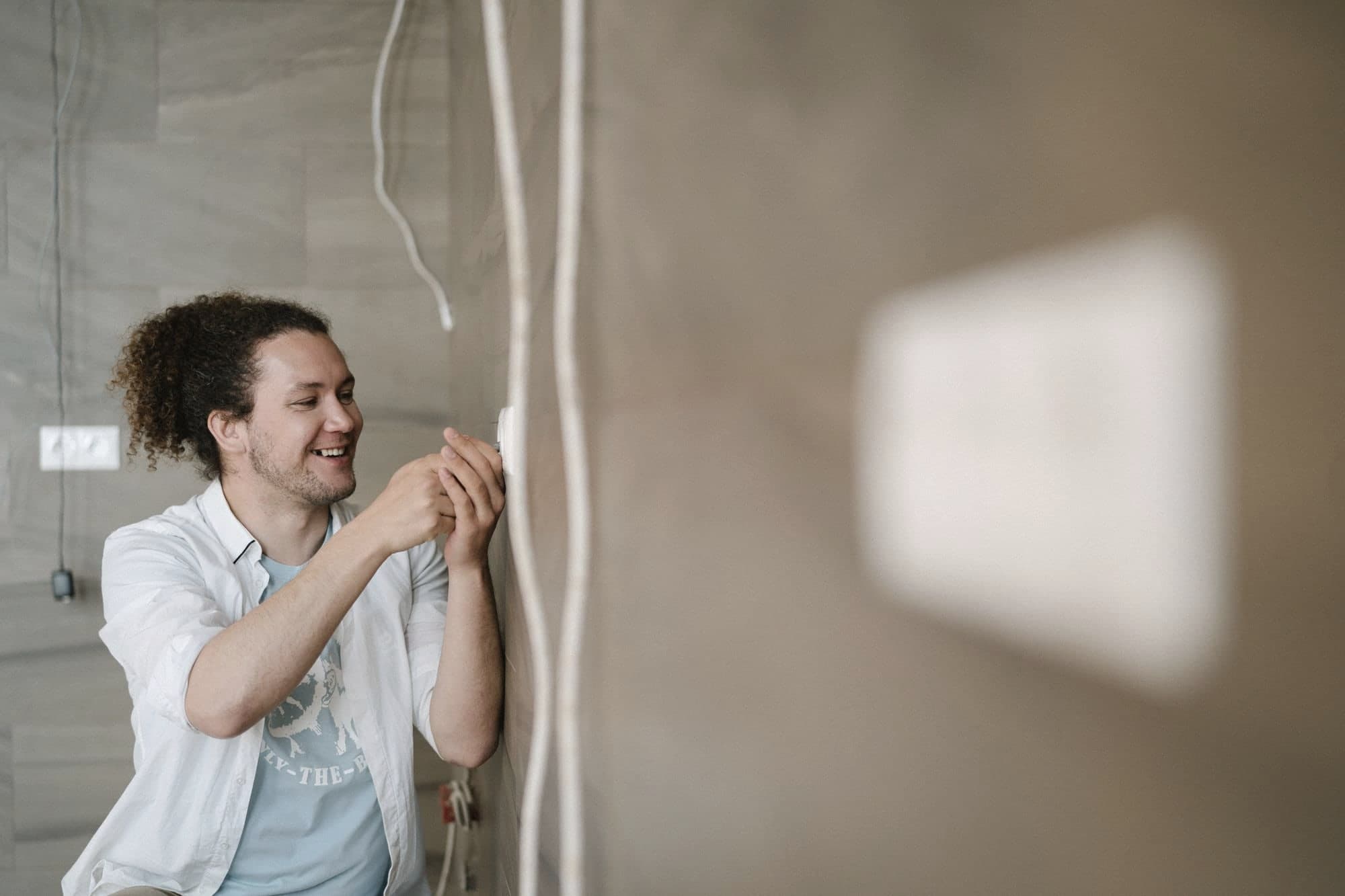 Un elettricista sorridente al lavoro su una presa.